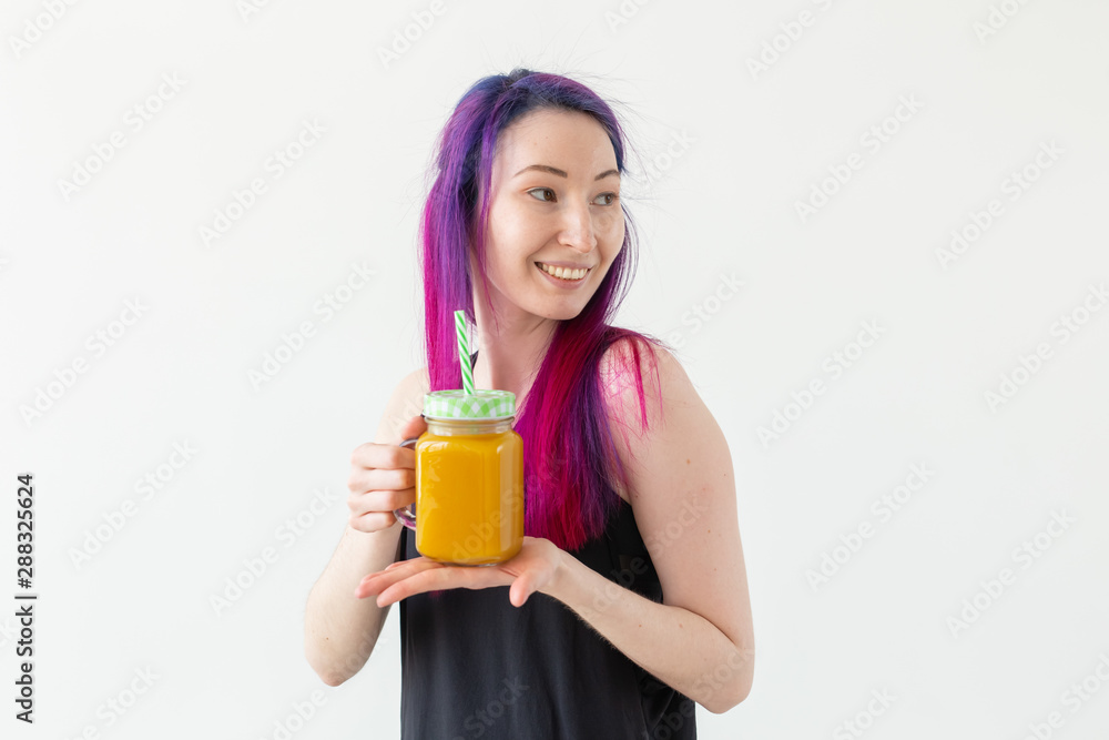 Cute young mixed race hipster girl with colored hair drinks fruit smoothie before starting a yoga class on a white background with copy space. Healthy lifestyle concept. Copyspase. Cute young mixed race hipster girl with colored hair drinks fruit smoothie before starting a yoga class on a white background with copy space. Healthy lifestyle concept. Copyspase.