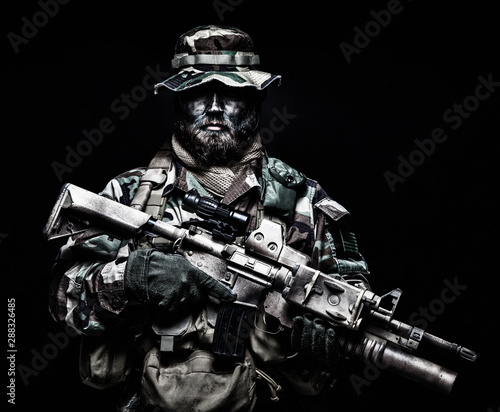Commando soldier in battle ammunition, armed rifle photo