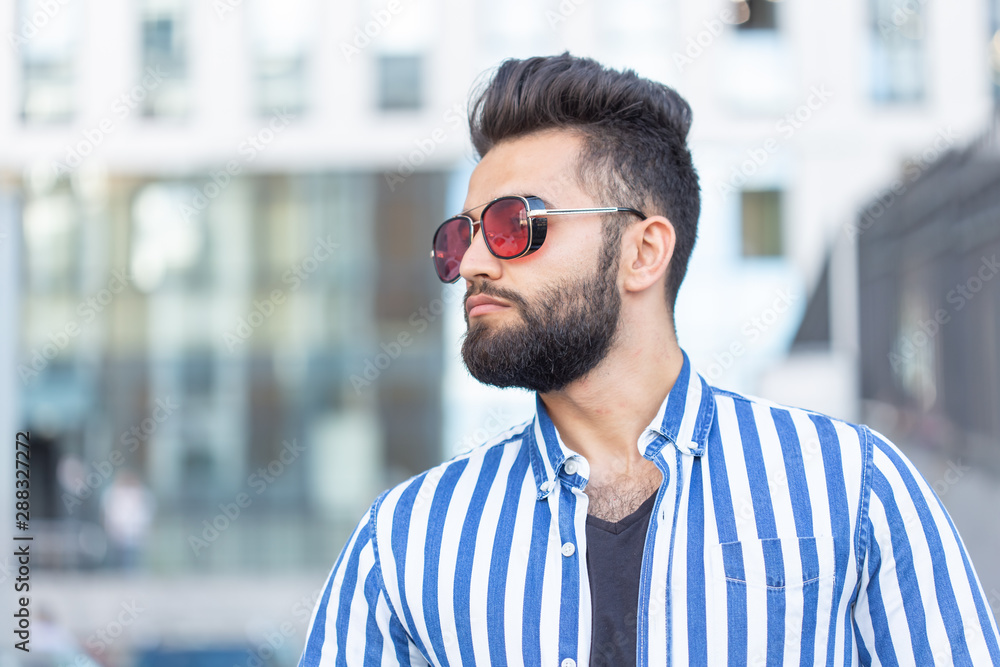 Portrait of cheerful positive stylish student guy in glasses with a mustache and beard outdoors. The concept of successful cheerful people. Portrait of cheerful positive stylish student guy in glasses with a mustache and beard outdoors. The concept of successful cheerful people.