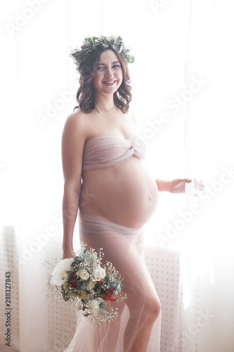 Beautiful pregnant woman on neutral background. Expectant closeup picture. Future mother portrait on pastel background. photo