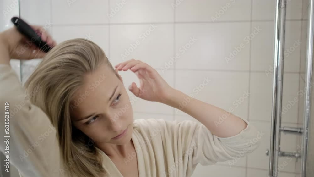 Woman brushing hair in restroom Woman brushing hair in restroom