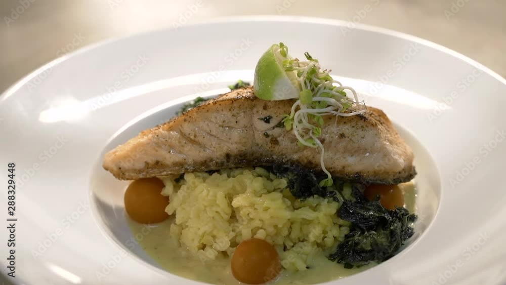 Fresh salmon steak with rice & lime wedge served on white plate in restaurant. Close up rotating. Fresh salmon steak with rice & lime wedge served on white plate in restaurant. Close up rotating.