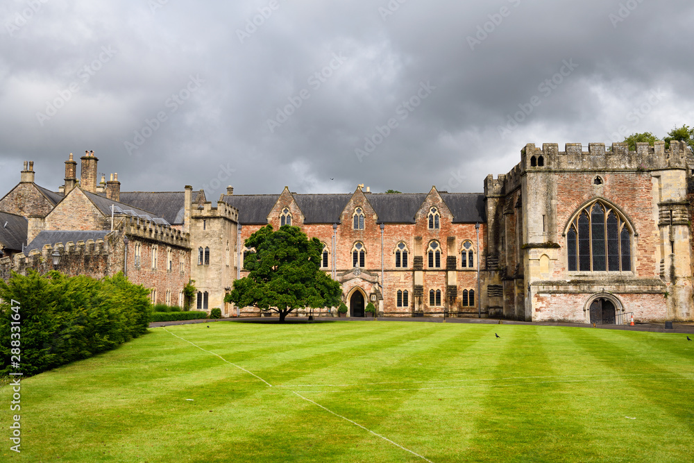 Bishop's Palace with Chapel and green Croquet Lawn under cloudy sky in Wells Somerset England Bishop's Palace with Chapel and green Croquet Lawn under cloudy sky in Wells Somerset England