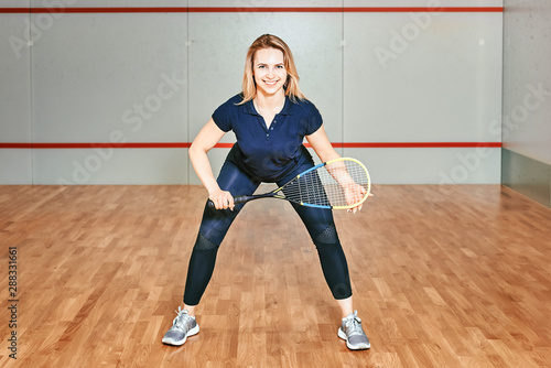 Portrait of a sporty blonde woman. young athletic girl holding squash tennis racquet.