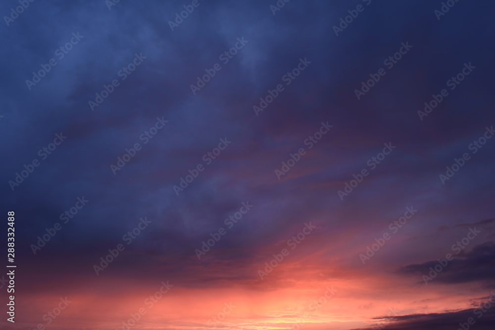 Cloudy blue sky in the bright yellow and red sunlight of sunset Cloudy blue sky in the bright yellow and red sunlight of sunset