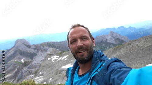 Young, happy man taking selfie photo in mountains, super slow motion