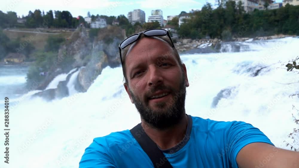Young, happy man taking selfie photo by waterfall, super slow motion Young, happy man taking selfie photo by waterfall, super slow motion