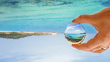 Hand holding a crystal ball with a ocean scene inside