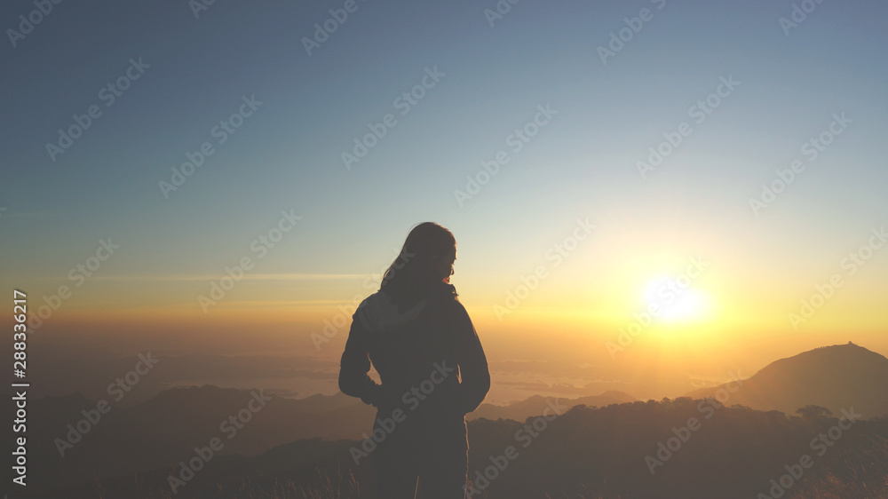 An asian girl is happy with the beautiful sunset and wonderful nature at the mountain