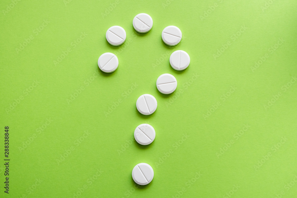 Question mark made of medicine tablets on a green background. Isolated. Question mark made of medicine tablets on a green background. Isolated.