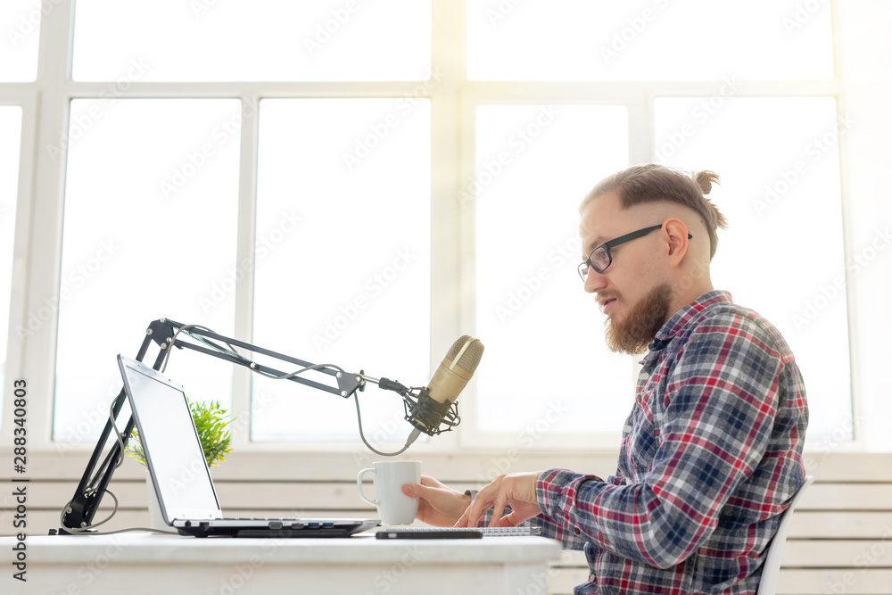Radio host, streamer and blogger concept - Handsome man working as radio host at radio station sitting in front of microphone Radio host, streamer and blogger concept - Handsome man working as radio host at radio station sitting in front of microphone