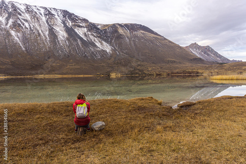 Rear view of young woman taking rest against snow-capped mountains and lake during winter season in Patagonia, Argentina