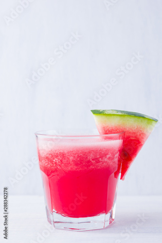 Watermelon drink in glasses with slices of watermelon. Watermelon smoothies on white background. Summer healthy drink for vegetarian. Copy space