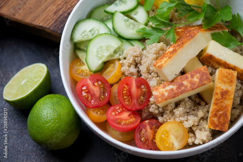 Power bowl with quinoa, fried cheese, cherry tomatoes, cucumber and parsley, elevated view, close-up