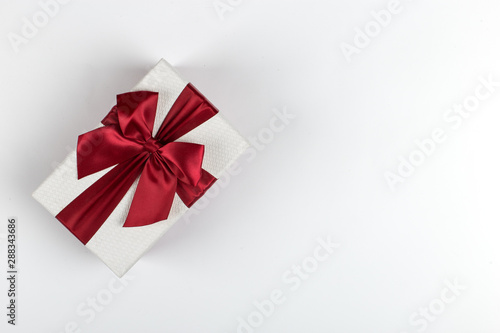 Gift with a red ribbon and a bow on a white background, copy space.