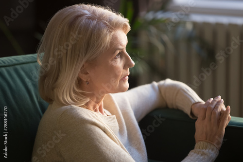 Photos Pensive elderly woman look in distance thinking or mourning