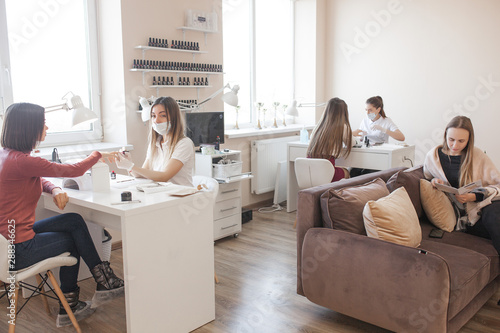 Manicurist making a manicure in the salon. Master servising her client. Nails care procedure.