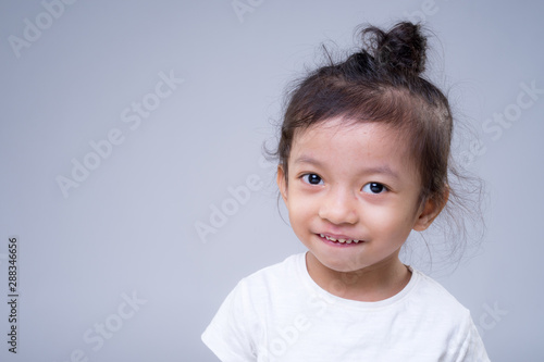 Portrait of a cute and adorable Asian young girl full of expression over grey background.