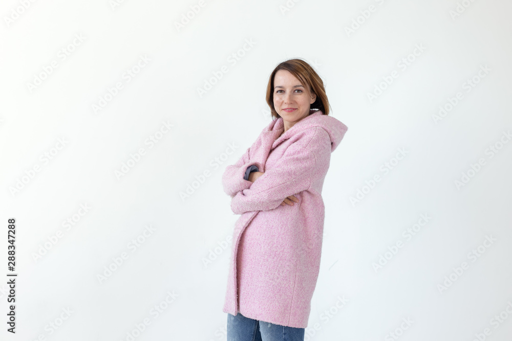 Charming young female model posing on a white background in a designer pink coat. The concept of a unique handicraft design. Advertising space, copyspace Charming young female model posing on a white background in a designer pink coat. The concept of a unique handicraft design. Advertising space, copyspace