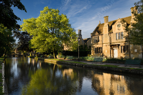 The Victoria Hall in morning sun with reflection on River Windrush in Bourton-on-the-Water Cotswolds England