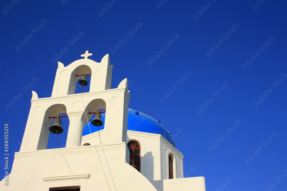 White bell tower and blue dome of the church in Oia, Santorini (Thira) in Greece