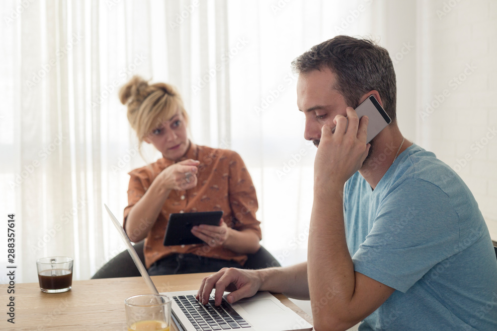 Couple sitting by the table. He is having a phone call. Couple sitting by the table. He is having a phone call.