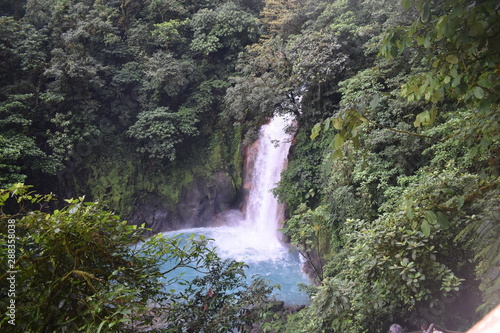 Beautiful waterfall of turquoise blue water  surrounded by green tropical vegetation.