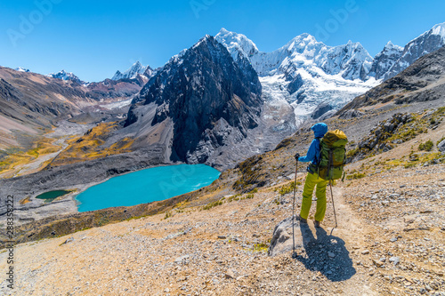 Girl hiking by stunning lake Juraucocha, San Antonio pass with view to Siula Grande peak, Huayhuash range, Huaraz, Ancash, Peru photo