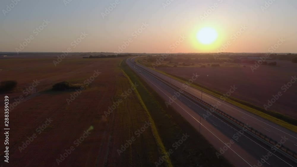 Many Cars is Moving Setting Sun. Aerial Shot Of Vehicle On Road In Beautiful Countryside in Sunset. Aerial View of Cars on Road With Sunset In Background. Many Cars is Moving Setting Sun. Aerial Shot Of Vehicle On Road In Beautiful Countryside in Sunset. Aerial View of Cars on Road With Sunset In Background.