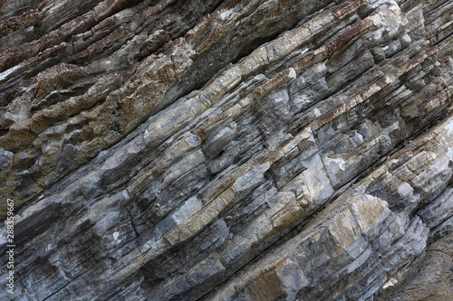 Background on the basis of the texture of rock. Gray-brown stone texture with inclined weathered stripes © avkost