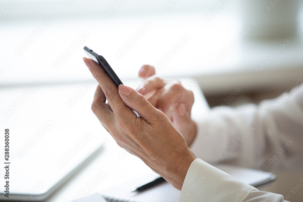 Close up of woman hold cellphone using internet at workplace Close up of woman hold cellphone using internet at workplace