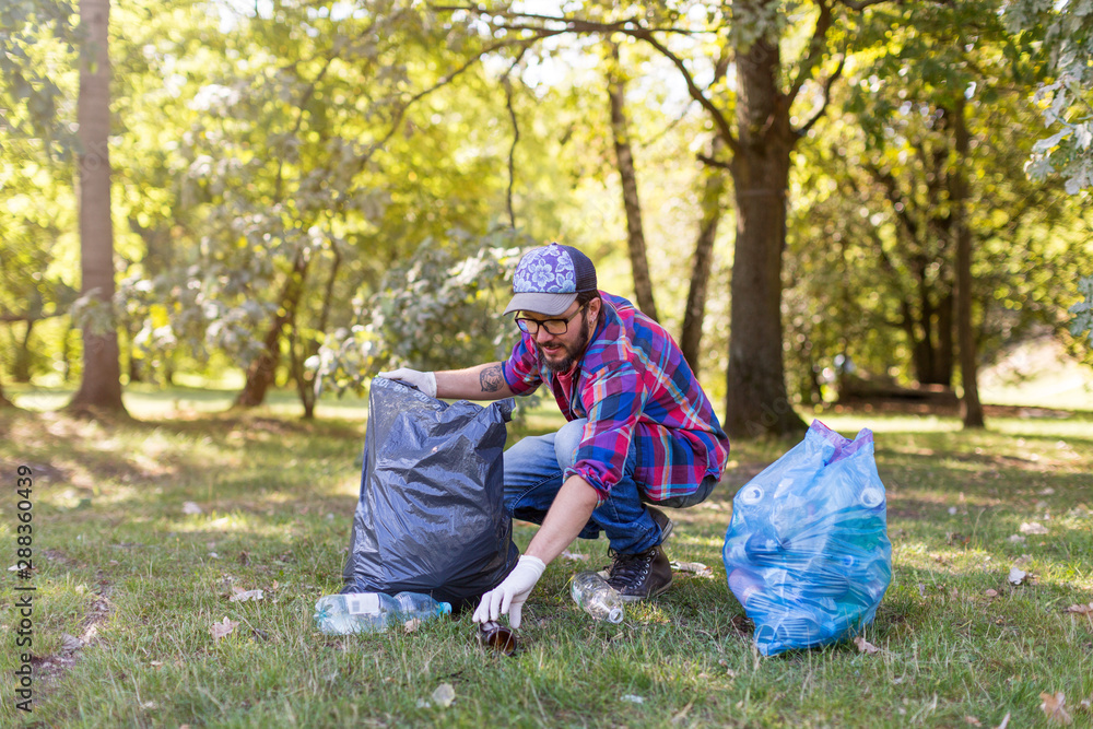 Young man picking up litter in his local park Young man picking up litter in his local park
