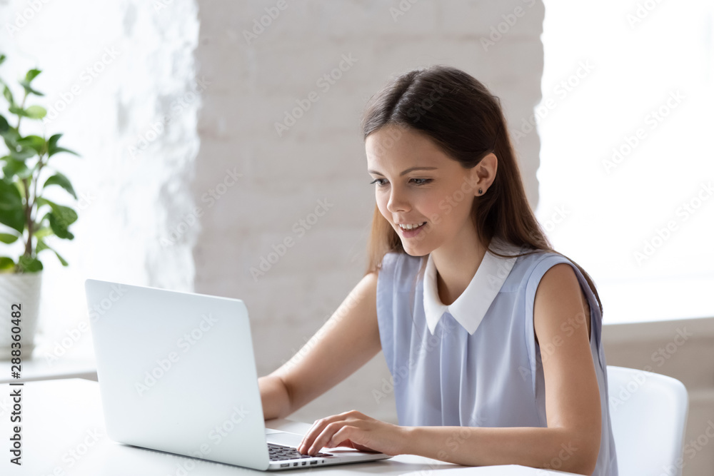 Focused young woman busy working on laptop in office Focused young woman busy working on laptop in office