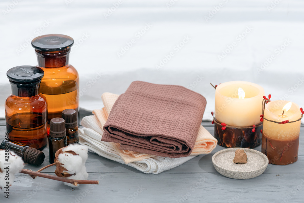 Aromatherapy oil bottles, burning candles and towels on a wooden floor background. Aromatherapy oil bottles, burning candles and towels on a wooden floor background.