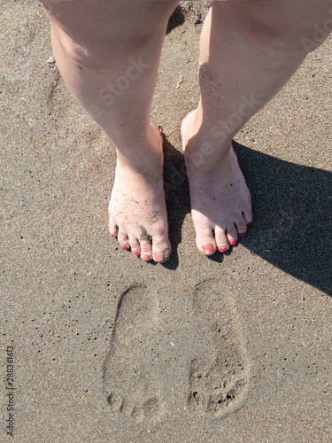 Human footprints - undefined human legs walking on the beach