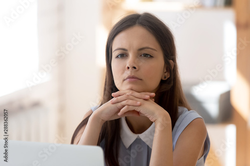 Pensive female employee distracted from work thinking