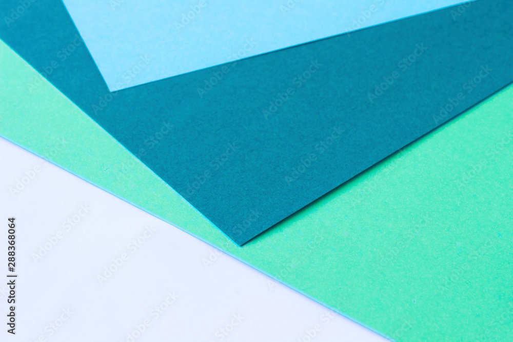 Four colored papers with blue, green, turquoise and white colors in the form of a triangle. Background, abstraction Four colored papers with blue, green, turquoise and white colors in the form of a triangle. Background, abstraction