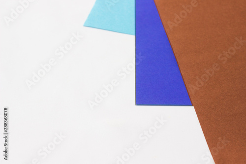 Three colored papers with blue, violet and brown colors on white in the form of a triangle. Background, abstraction