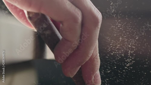 Slow motion woodworker hand sanding walnut board with sand block