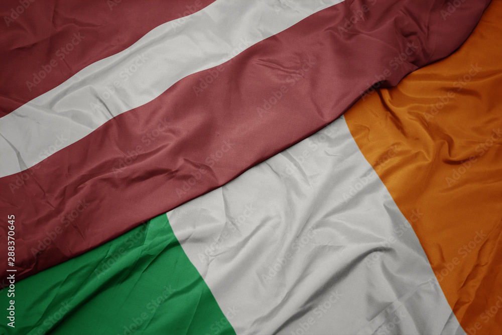 waving colorful flag of ireland and national flag of latvia. waving colorful flag of ireland and national flag of latvia.