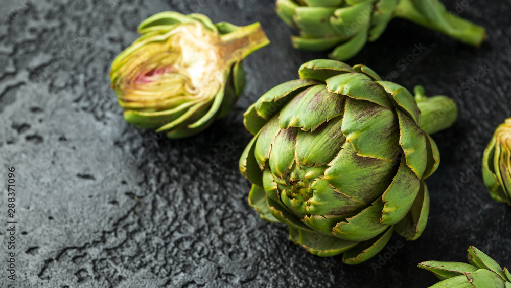 Obraz premium Fresh raw organically grown artichoke flower buds on dark background