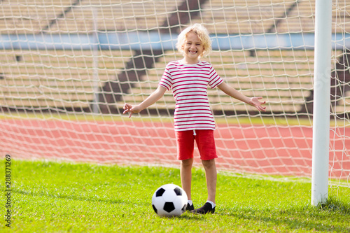 Kids play football. Child at soccer field.