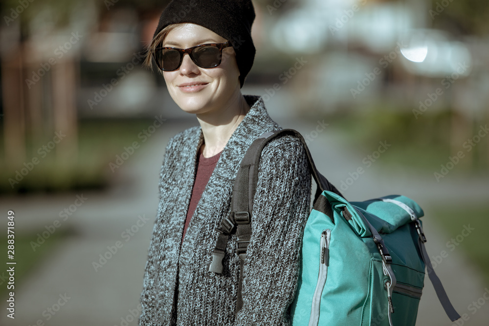 Lifestyle fashion portrait of young stylish hipster woman walking on the street