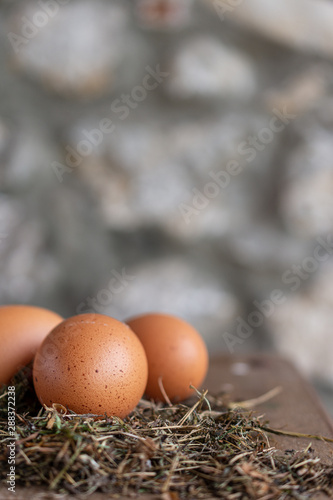 Top view of farm eggs on hay and wooden table in vertical with copy space