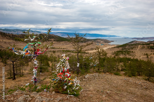 A sacred place of power with ribbons at Lake Baikal on a hill. Traditions of Buryatia in Russia. Shamanism of the island of Olkhon. photo