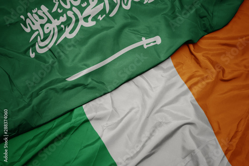 waving colorful flag of ireland and national flag of saudi arabia.