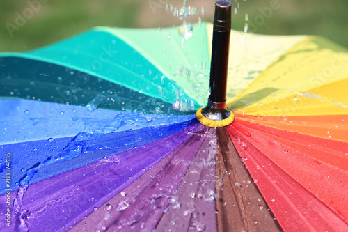 Krople deszczu spadające na parasol w kolorach tęczy, deszczowa pogoda. © Stanisław Błachowicz