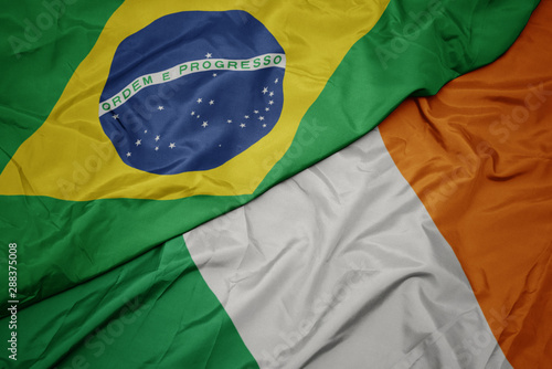 waving colorful flag of ireland and national flag of brazil.