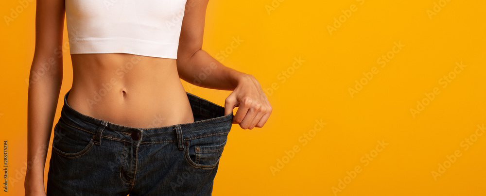 Unrecognizable Girl In Oversize Jeans Posing On Yellow Background, Cropped - obrazy, fototapety, plakaty 