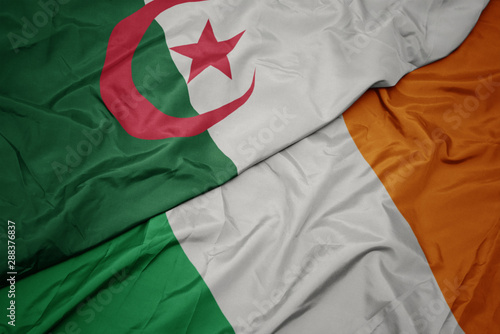 waving colorful flag of ireland and national flag of algeria.